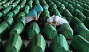 POTOCARI, BOSNIA AND HERZEGOVINA - JULY 10: Two young Muslim women weep over one of 613 coffins of victims of the 1995 Srebrenica massacre in a hall at the Potocari cemetery and memorial near Srebrenica on July 10, 2011 in Potocari, Bosnia and Herzegovina. The newly-identified remains of the 613 victims are scheuled to be buried in a ceremony to be held on July 11, the 16th anniversary of the massacre. At least 8,3000 Bosnian Muslim men and boys who had sought safe heaven at the U.N.-protected enclave at Srebrenica were killed by members of the Bosnian Serb army under the leadership of General Ratko Mladic, who is currently facing charges of war crimes in The Hague, during the Bosnian war in 1995. A Dutch court recently found the Dutch government responsible for the deaths of three of the victims when Dutch U.N. peacekeepers handed the three men, who had been working on the Dutch base in Srebrenica, over to Serbian soldiers. (Photo by Sean Gallup/Getty Images)
